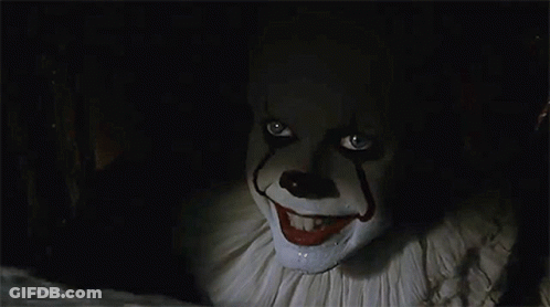 A Close Up Of A Clown With A Smile On His Face In A Dark Room . GIF