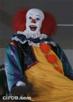 A Close Up Of A Clown With Red Hair And A White Face GIF