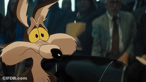 A Close Up Of A Coyote With A Man In A Suit Behind Him GIF