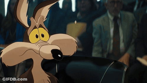 A Close Up Of A Coyote With A Man In A Suit Behind Him GIF