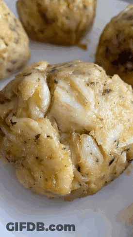 A Close Up Of A Crab Cakes On A White Plate GIF