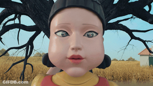 A Close Up Of A Doll 'S Face With A House In The Background GIF