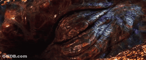 A Close Up Of A Dragon 'S Eye With A Glowing Orange Pupil GIF