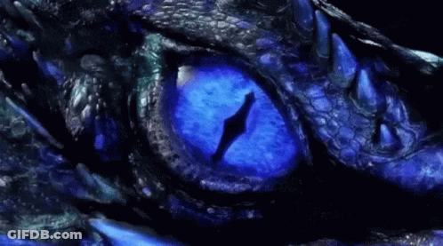 A Close Up Of A Dragon 'S Eye With Blue Light Coming Out Of It GIF