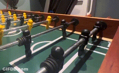 A Close Up Of A Foosball Table With Yellow And Black Players GIF