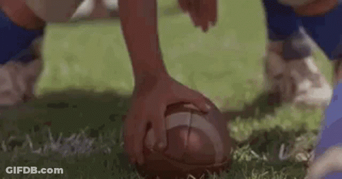 A Close Up Of A Football Being Kicked By A Player On A Field . GIF