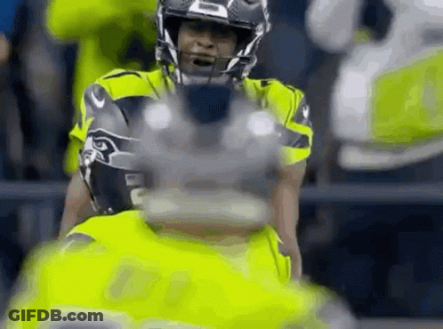 A Close Up Of A Football Player Wearing A Helmet And Holding A Football . GIF
