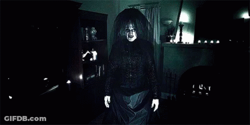 A Close Up Of A Ghost With Glowing Hands In A Dark Room GIF