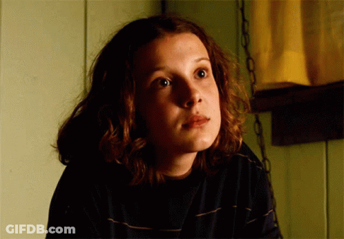A Close Up Of A Girl 'S Face With A Yellow Curtain Behind Her GIF