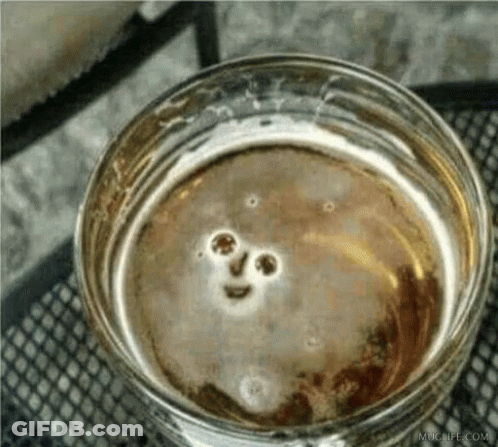 A Close Up Of A Glass Of Beer With A Smiley Face In It GIF
