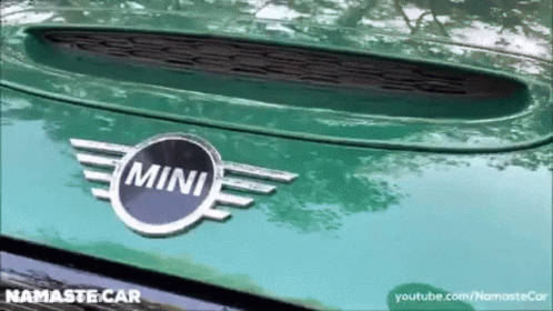 A Close Up Of A Green Mini Car With A Namaste Car Logo GIF