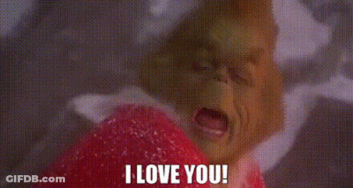 A Close Up Of A Grinch Holding A Heart And Saying `` I Love You '' . GIF