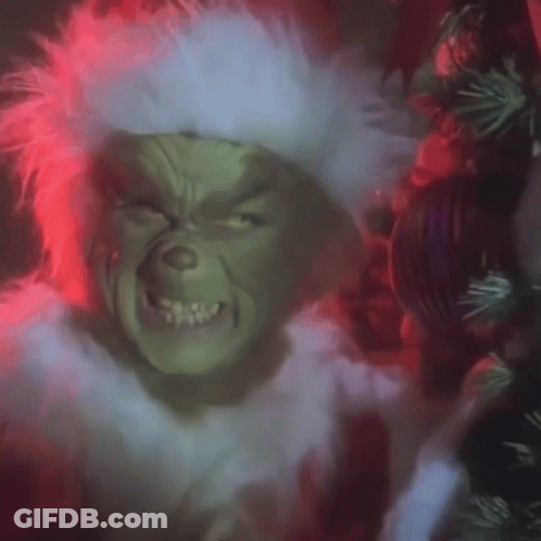 A Close Up Of A Grinch 'S Face With A Wreath In The Background . GIF