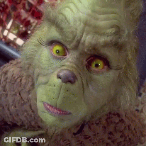 A Close Up Of A Grinch 'S Face With Bright Yellow Eyes GIF
