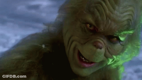 A Close Up Of A Grinch 'S Face With Glowing Green Eyes . GIF