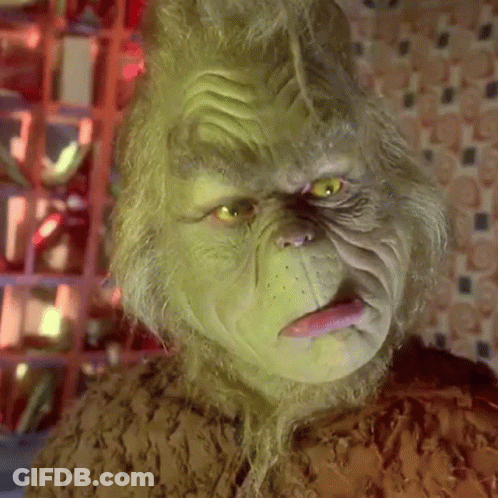 A Close Up Of A Grinch 'S Face With His Tongue Sticking Out . GIF