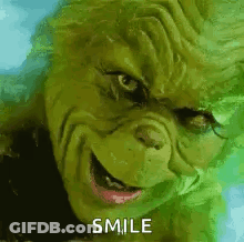 A Close Up Of A Grinch 'S Face With The Words `` Smile '' Written On It . GIF