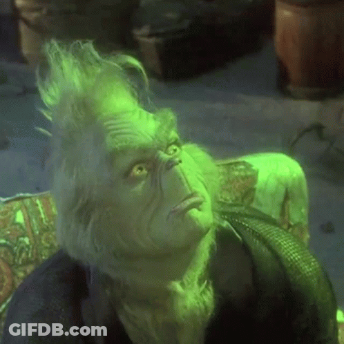 A Close Up Of A Grinch Sitting On A Couch With His Eyes Closed . GIF
