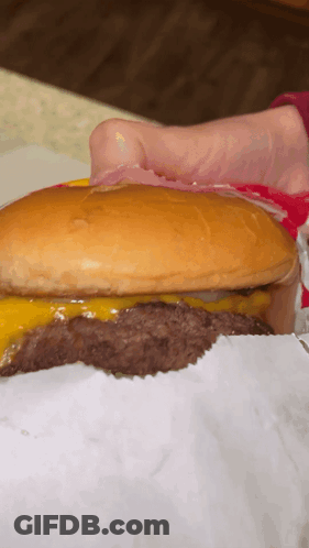 A Close Up Of A Hamburger With A Bun And Cheese GIF