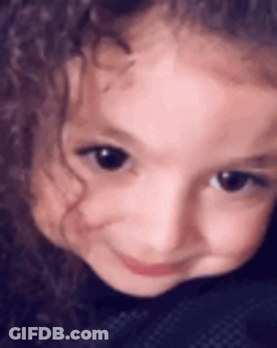 A Close Up Of A Little Girl 'S Face With Curly Hair . GIF