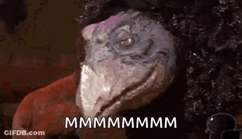 A Close Up Of A Lizard 'S Face With The Words `` Mmmmmm '' Written On It . GIF