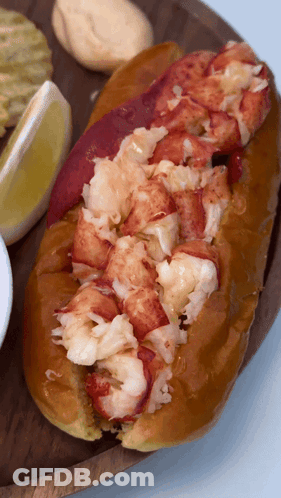A Close Up Of A Lobster Roll On A Wooden Tray GIF