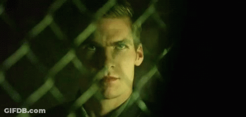 A Close Up Of A Man Behind A Chain Link Fence . GIF