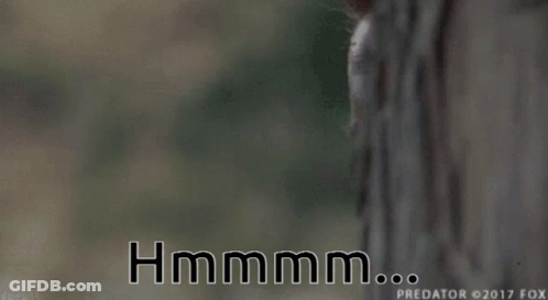 A Close Up Of A Man Behind A Tree With The Words Hmmmm GIF