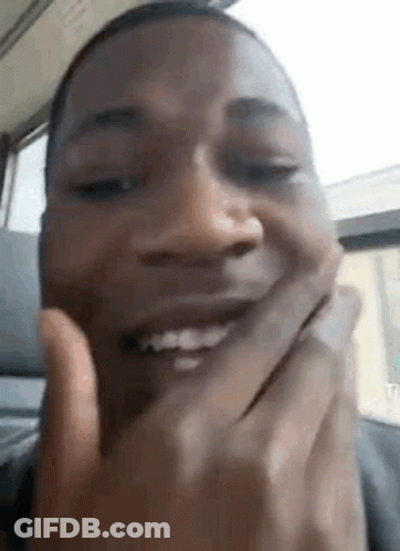 A Close Up Of A Man Covering His Mouth With His Hands While Smiling . GIF