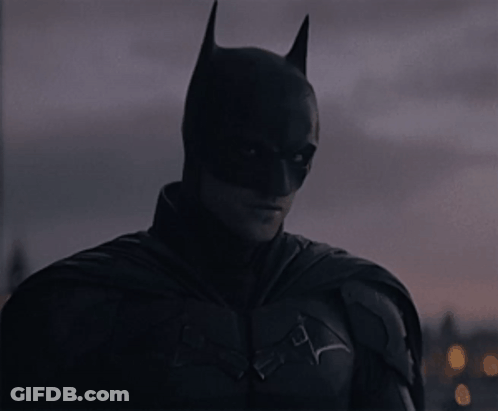 A Close Up Of A Man In A Batman Costume Looking At The Camera GIF