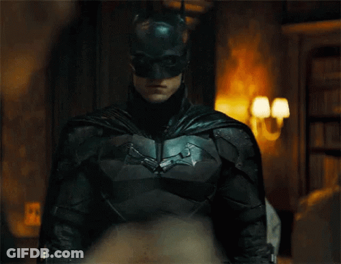 A Close Up Of A Man In A Batman Suit And Mask Standing In A Room . GIF