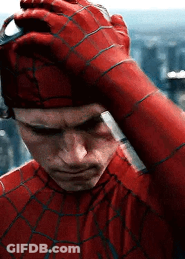 A Close Up Of A Man In A Spiderman Costume Holding His Hand To His Head . GIF