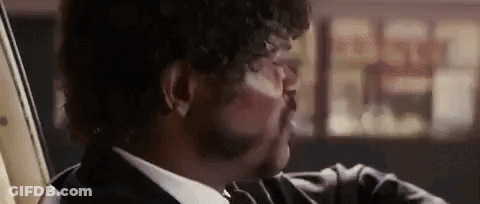 A Close Up Of A Man In A Suit And Tie Holding A Gun . GIF