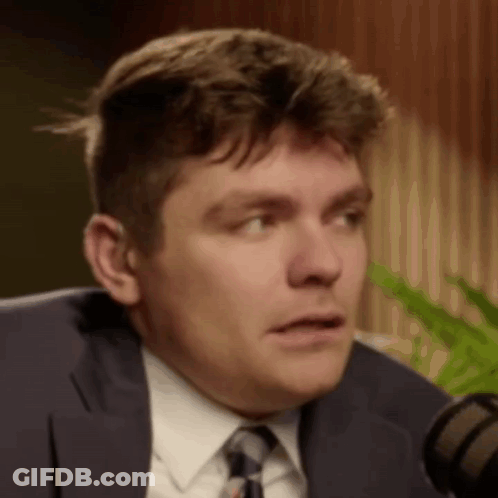 A Close Up Of A Man In A Suit And Tie Talking Into A Microphone . GIF