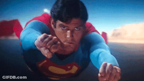 A Close Up Of A Man In A Superman Costume Flying In The Air . GIF