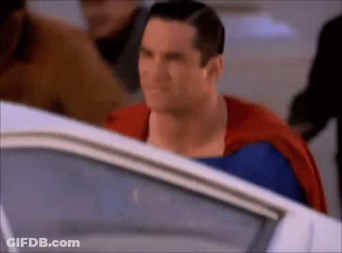 A Close Up Of A Man In A Superman Costume Standing Next To A White Car . GIF