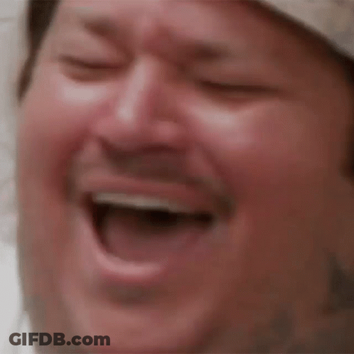 A Close Up Of A Man Laughing With His Eyes Closed And His Mouth Open . GIF