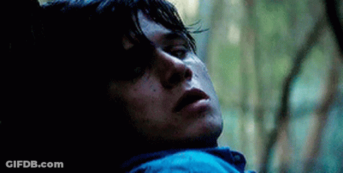 A Close Up Of A Man Laying Down In The Woods With His Eyes Closed . GIF