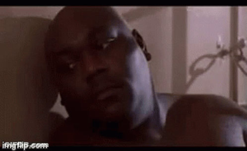 A Close Up Of A Man Laying On A Bed Looking At The Camera . GIF