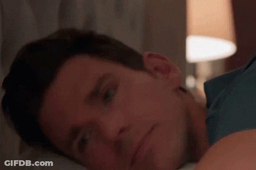 A Close Up Of A Man Laying On A Bed With His Head On His Arm . GIF