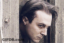 A Close Up Of A Man 'S Face Against A Wooden Fence GIF