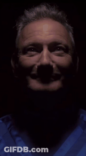 A Close Up Of A Man 'S Face In A Dark Room GIF