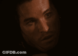 A Close Up Of A Man 'S Face In A Dark Room Looking At The Camera GIF