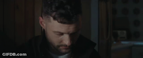 A Close Up Of A Man 'S Face In A Dark Room . GIF