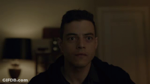 A Close Up Of A Man 'S Face In A Dark Room With A Lamp In The Background GIF