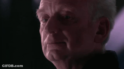 A Close Up Of A Man 'S Face In A Dark Room With A Purple Light Behind Him . GIF