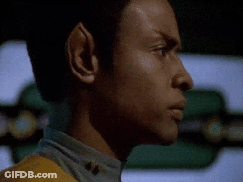 A Close Up Of A Man 'S Face In A Dark Room With A Yellow Shirt On . GIF