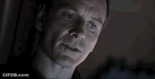 A Close Up Of A Man 'S Face In A Dark Room With Smoke Coming Out Of His Mouth . GIF