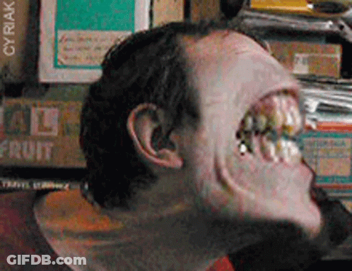 A Close Up Of A Man 'S Face In Front Of A Stack Of Fruit Boxes GIF