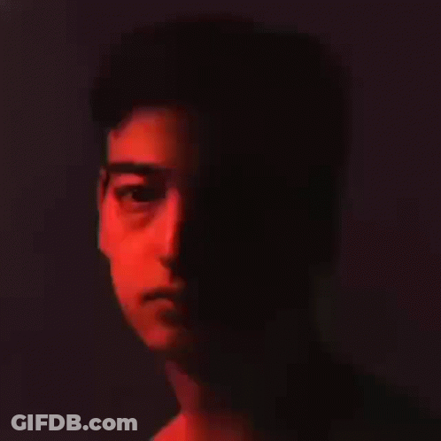 A Close Up Of A Man 'S Face In The Dark With A Red Light Shining On It . GIF